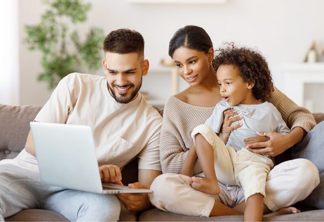 Family enjoying time together on a couch, using a laptop, illustrating the importance of family health and accessible medical care at UCO Medical Clinic.